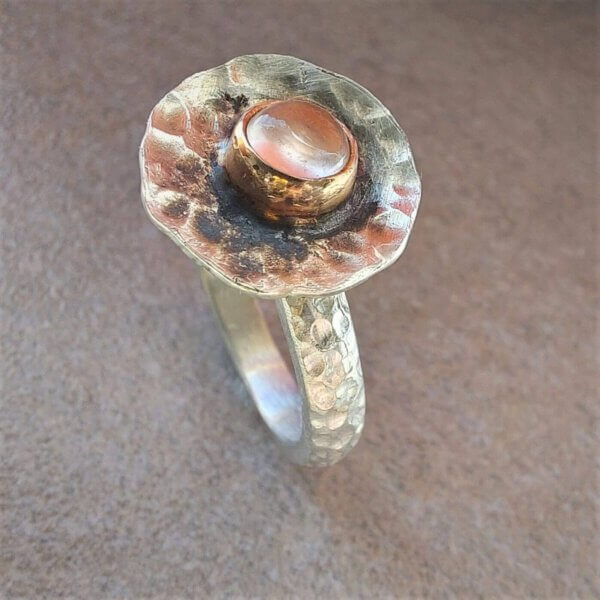 Gehamerde zilveren ring met een rozenkwarts in roségouden zetting